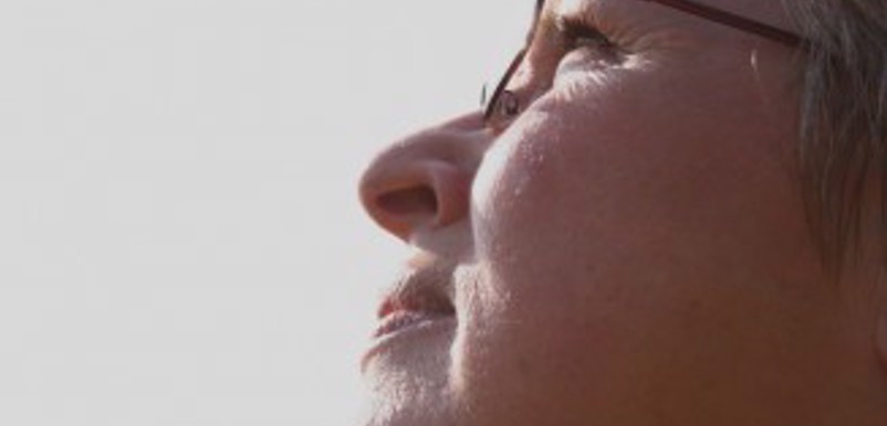 Närbild på en kvinna med glasögon som tittar mot solen