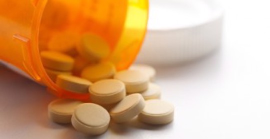 En medicinburk med uthällda tabletter