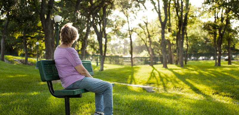 En kvinna sitter på en parkbänk och tittar bort
