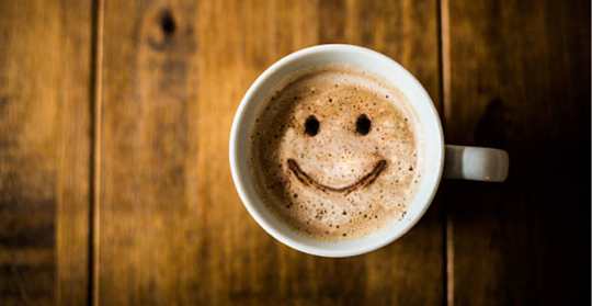 En kaffekopp uppifrån med en smiley ritad i skummet