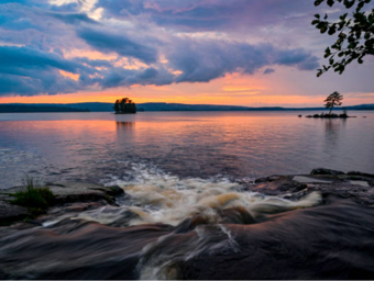 Rinnande tillflöde till en sjö vid solnedgången